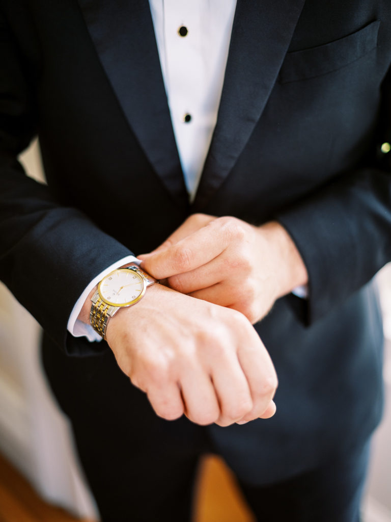 The groom adjusts his watch before the wedding day at Brecknock Hall begins.