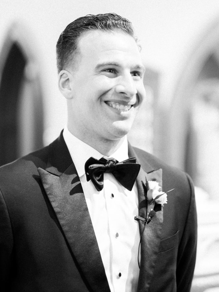 The groom, wearing The Black Tux and a boutonniere by Kim Jon designs sees his bride for the first time.