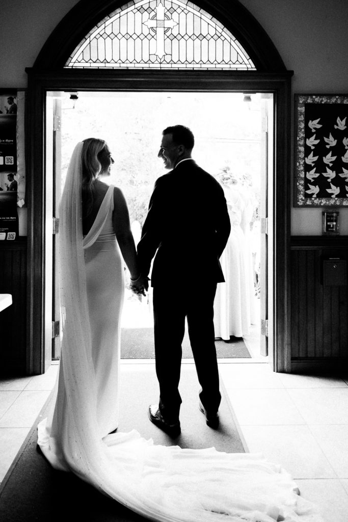 The bride and groom wearing pronovias and The Black Tux look at each other before walking outside to see their family and friends.