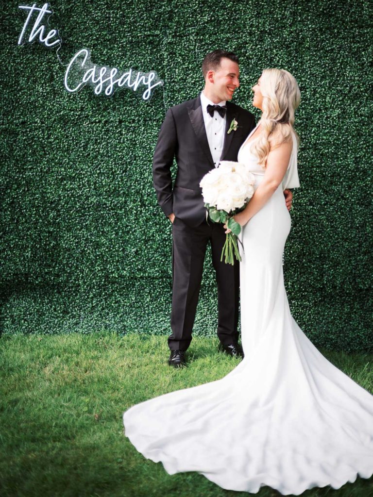 An intimate photograph of The bride and groom wearing pronovias and The Black Tux with flowers by Kim Jon designs during their Brecknock Hall wedding reception.