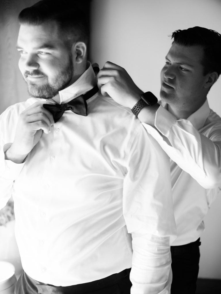 Bests man helps groom getting ready at Air BNB for his Long Island Vineyard Wedding.