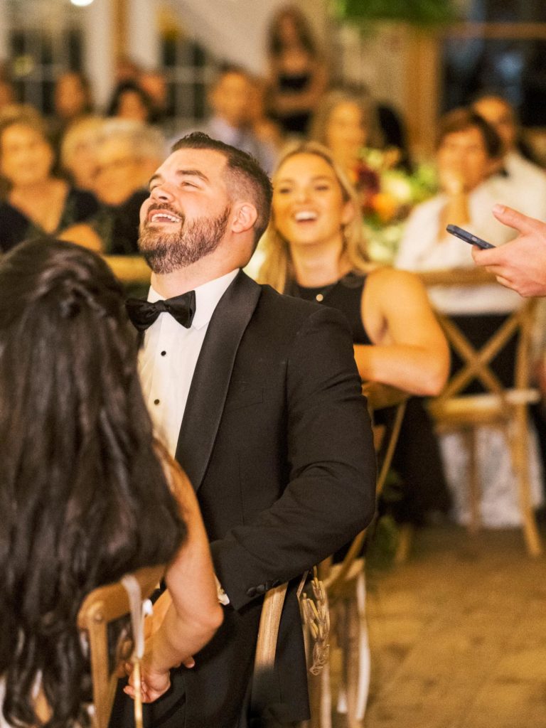 Groom laughs during speeches at Long Island Vineyard Wedding.