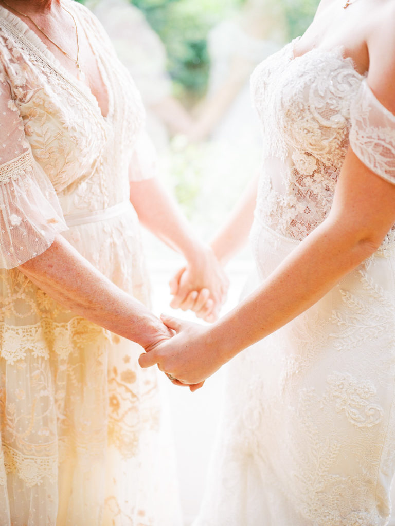 Bride and mom hold hands before Montauk wedding.