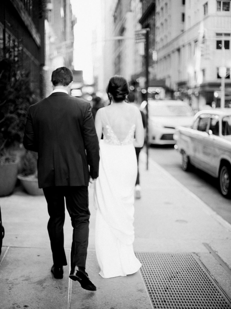 Bride and groom walk down city street in NYC before The Central Park Boathouse Wedding.